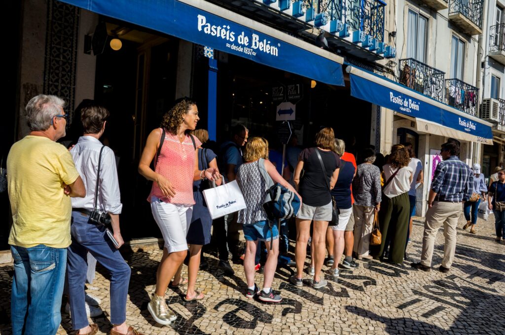 A line of tourists outside a pastry shop.