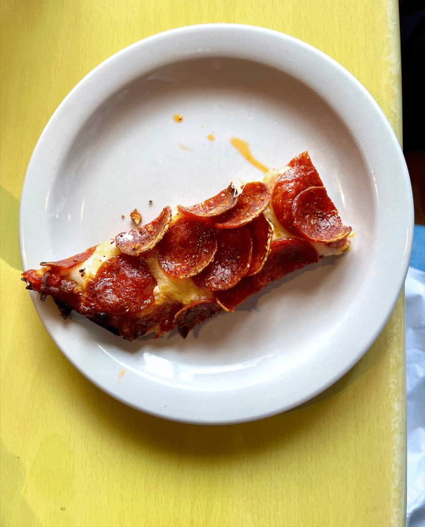 A top-down view of a thin piece of pepperoni pizza on a plate.