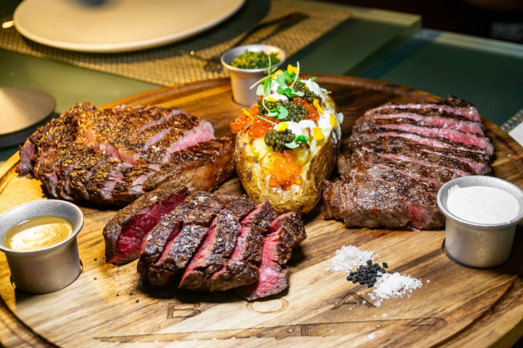 Three sliced stakes with an overloaded baked potato.