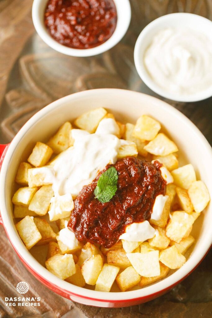 patatas bravas in a bowl with garlic aioli and bravas sauce in a small bowls.